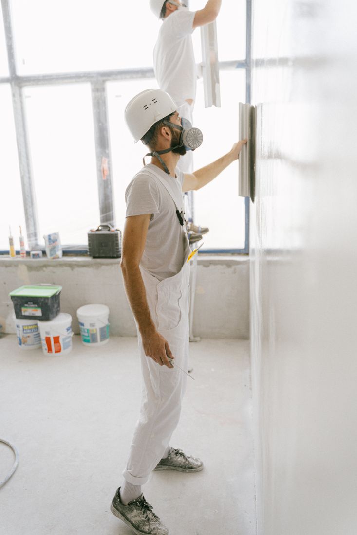 Renovation workers smoothing an interior wall